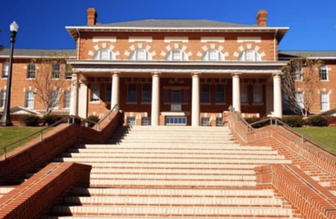 A historic red-brick campus building with a white-columned portico reached by a wide brick staircase
